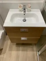 Close-up of the white basin in the Interior Apartment bathroom with chrome tap and toiletry cups